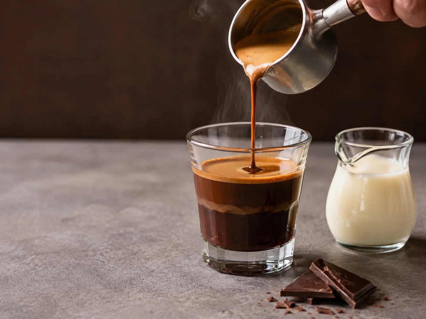 Espresso poured over thick dark chocolate with cream beside the glass for bicerin preparation