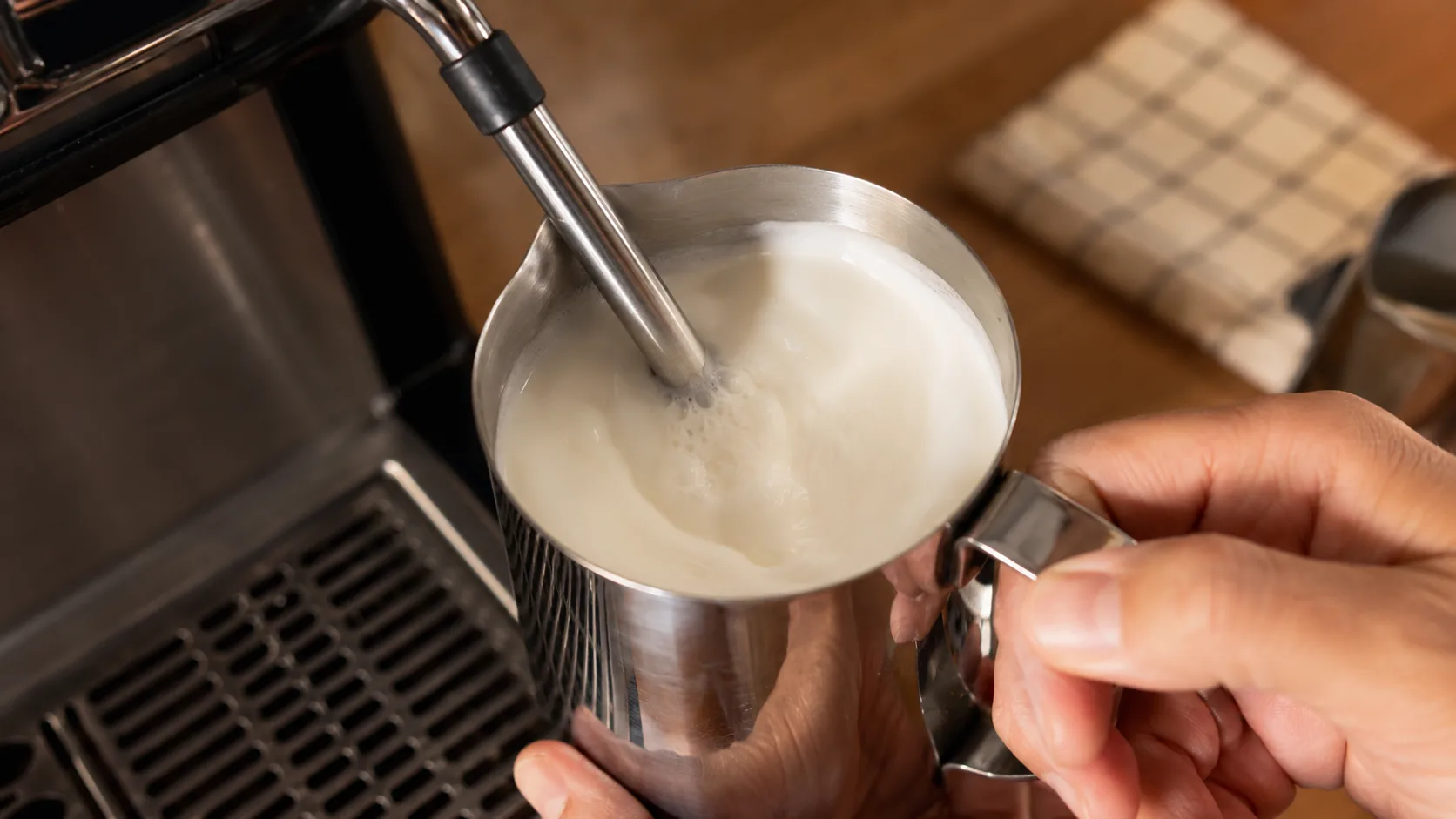 Half-and-half being steamed in a metal pitcher for breve coffee