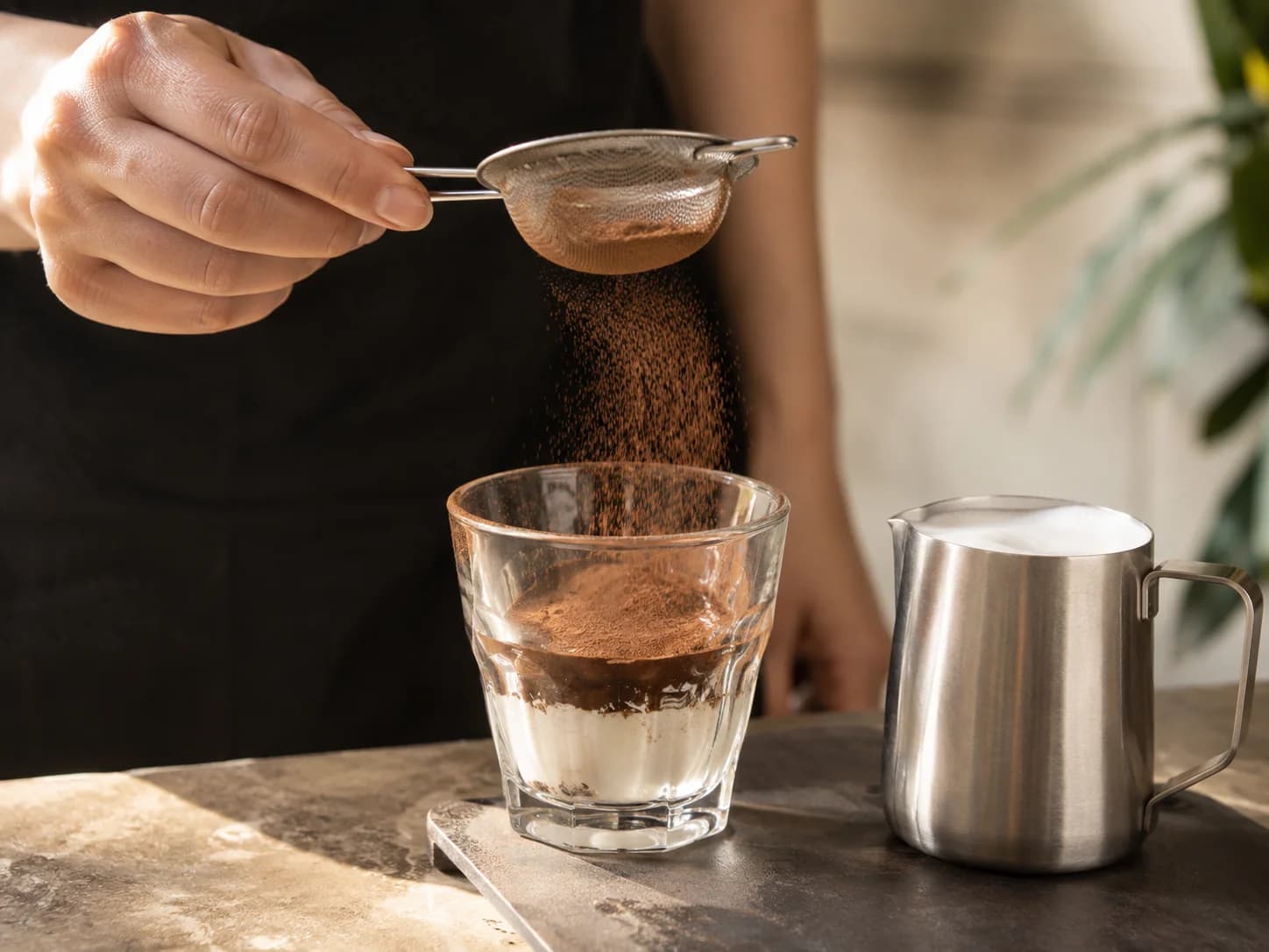 Caffe marocchino preparation with cocoa dusted into a glass before espresso and milk foam