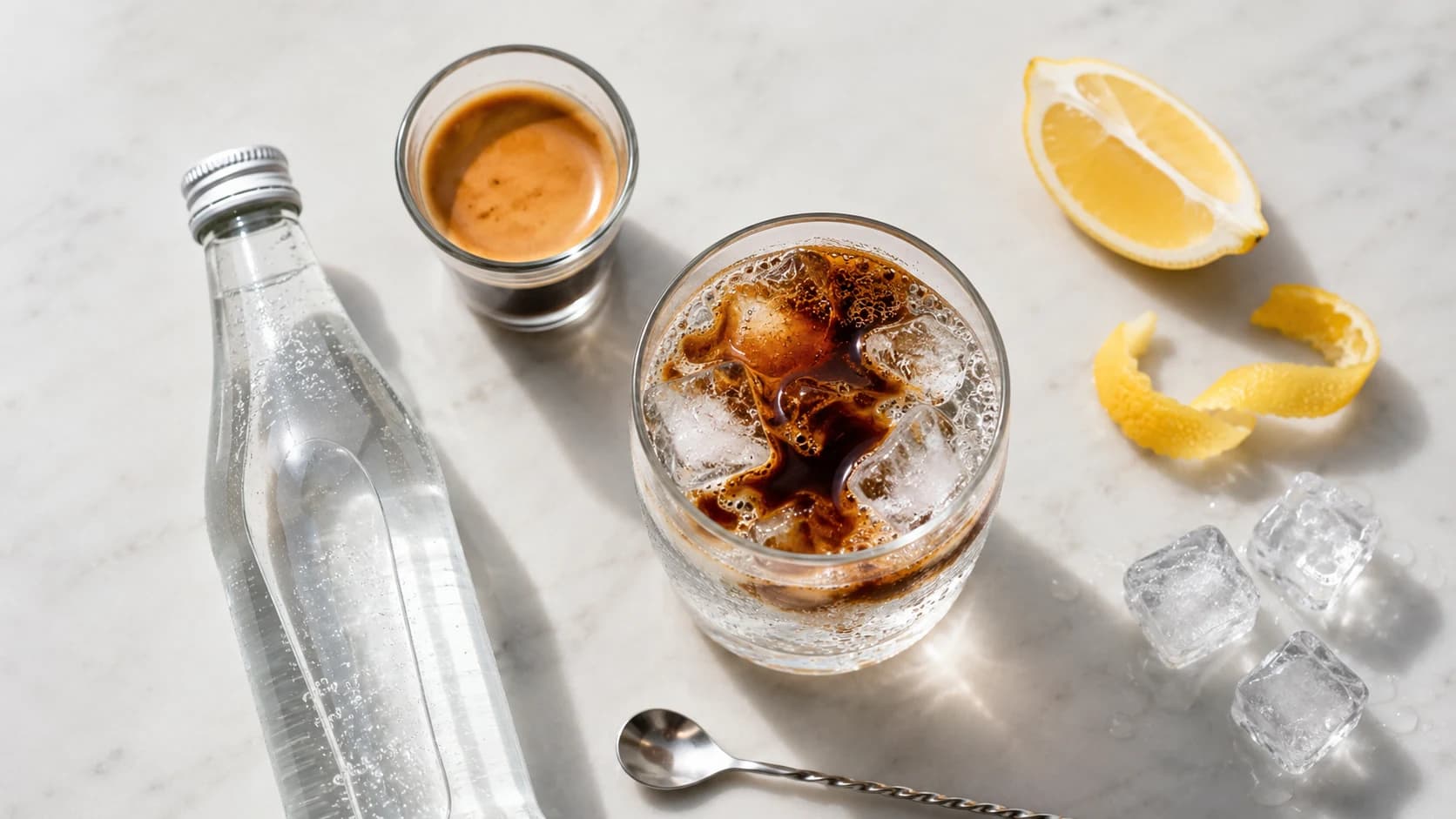 Coffee soda ingredients with espresso, sparkling water, lemon, and a glass of ice