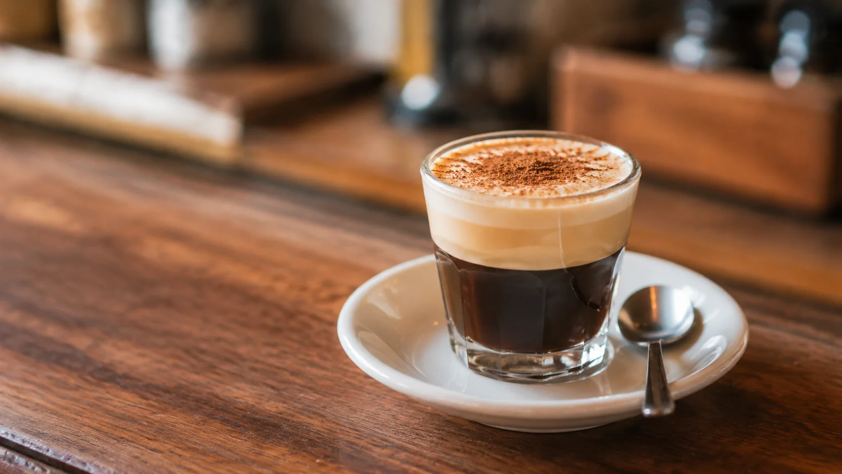 Cortadito in a small glass with espresso and milk layers on a cafe counter