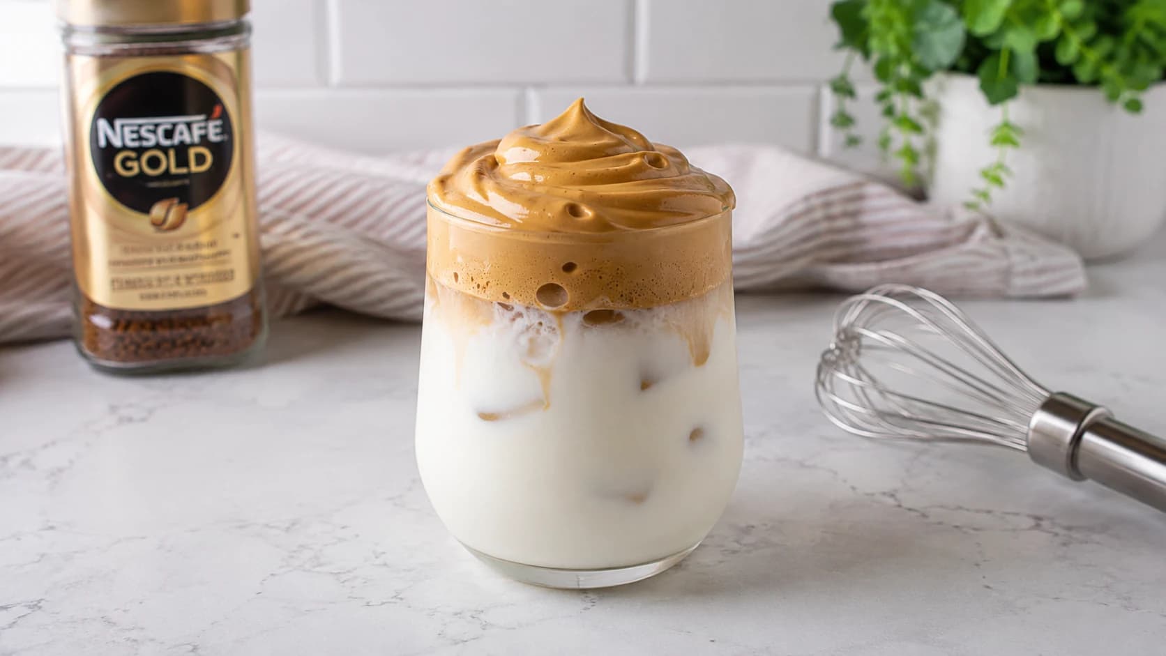 Dalgona coffee with a thick whipped instant coffee cap over iced milk