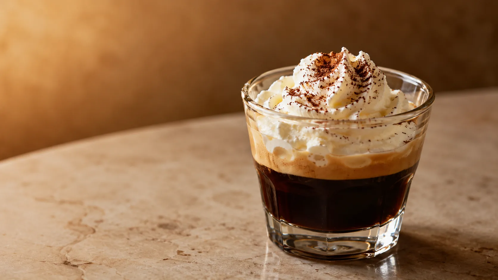 Espresso con panna topped with whipped cream and cocoa in a small glass