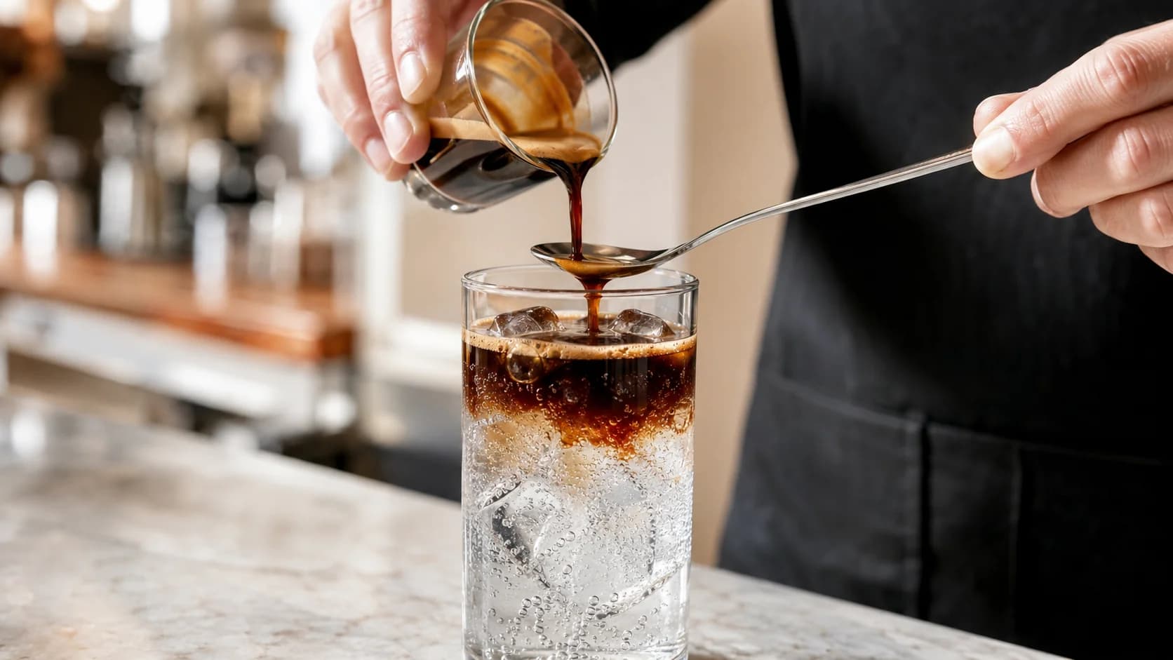 Espresso poured slowly over a spoon into chilled tonic water and ice