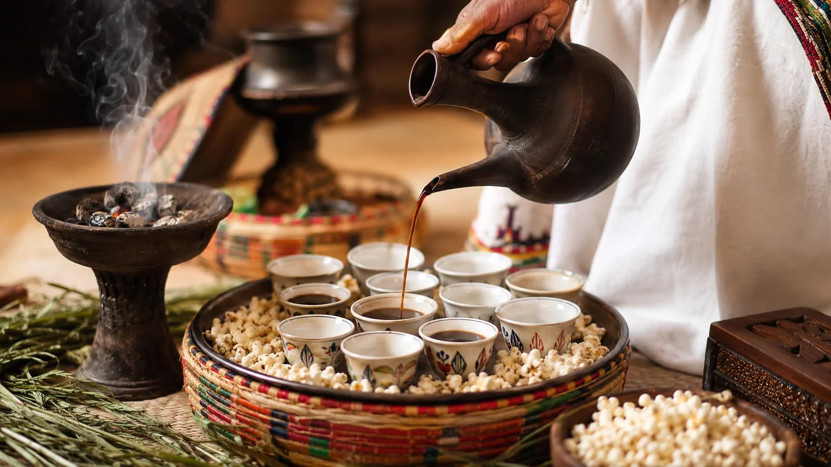Ethiopian coffee being poured from a jebena into small cups during a buna ceremony