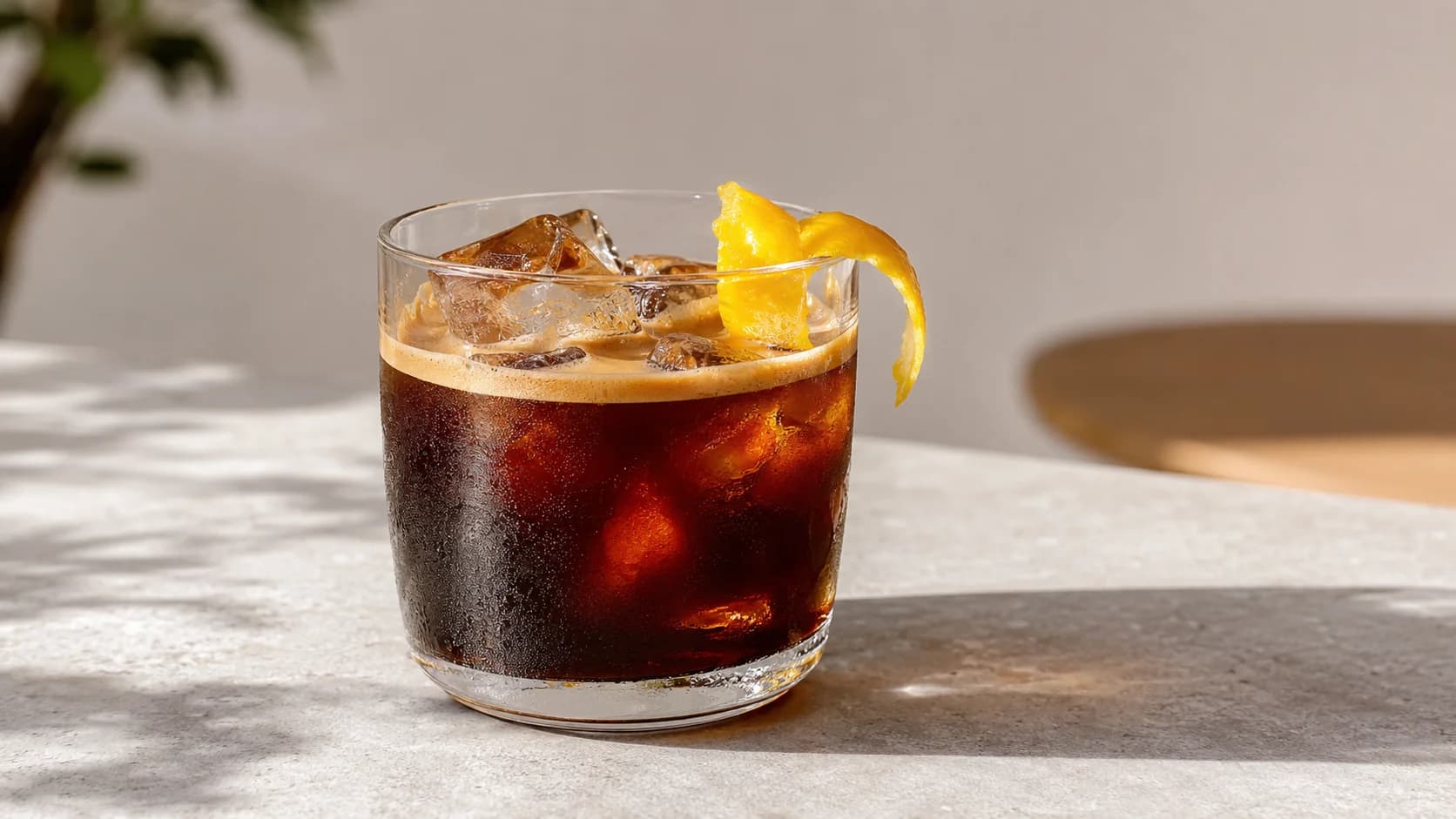 Small iced espresso served over large ice cubes with an optional lemon peel