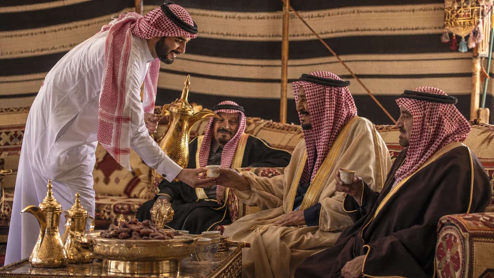 Saudi coffee being served from a dallah to guests seated in a majlis