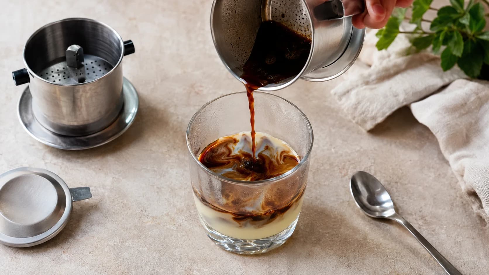 Vietnamese iced coffee preparation with phin coffee dripping over condensed milk